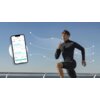 Na zdjęciu widać osobę w ciemnym stroju sportowym, wykonującą ćwiczenie na świeżym powietrzu, oraz smartfon z aplikacją pokazującą wykresy i dane takie jak "weight", "BMI" i "Body FAT%". W tle znajduje się niebo i balustrada, a wokół osoby widoczne są lin