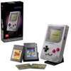 Na zdjęciu znajduje się zestaw klocków LEGO przedstawiający konsolę Game Boy z widocznym ekranem z napisem "Nintendo" oraz przyciskami w kolorze różowym. Obok konsoli znajdują się trzy kasety z grami, w tym jedna z napisem "Super Mario Land", a w tle wido