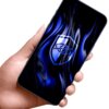 Na zdjęciu widoczny jest telefon trzymany w dłoni, na ekranie którego znajduje się niebieski wzór z symbolem oka w tarczy. Tło jest białe, a telefon ma ciemną obudowę.