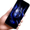 Na zdjęciu widać dłoń trzymającą smartfon z niebieskim, falistym wzorem na ekranie, na którym znajduje się symbol tarczy z okiem. Ekran jest pokryty szkłem ochronnym, które odbija światło.