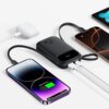 Na zdjęciu widoczny jest czarny powerbank z wyświetlaczem pokazującym "22.5W", do którego podłączone są dwa smartfony i białe etui na słuchawki. Na ekranie jednego z telefonów widnieje napis "Charging 60%".