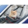 Na zdjęciu znajduje się fotelik samochodowy KONG Travel Secure Booster Seat umieszczony na jasnym siedzeniu samochodowym, z widocznym logo "KONG" na boku. W foteliku siedzi mały, puszysty piesek w czerwonej uprzęży.
