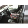 Na zdjęciu widać wnętrze samochodu z zamontowanym fotelikiem samochodowym KONG Travel Secure Booster Seat na przednim siedzeniu pasażera. Fotelik jest szary z czerwonymi akcentami i widocznym logo "KONG" na boku.