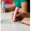Na zdjęciu widać rękę trzymającą różowe urządzenie z napisem "LAMAX", które jest używane do rysowania na kartce z widocznymi schematami i tekstem. W tle znajduje się druga osoba trzymająca podobne urządzenie w kolorze niebieskim.
