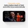 Smartfon wyświetla tryb filmowy z napisem "Cinematic mode Adds shallow depth of field and shifts focus automatically". Na ekranie widać scenę z dwoma osobami, a w prawym dolnym rogu znajduje się czerwony przycisk nagrywania.