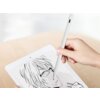 Na zdjęciu widać białą rękę trzymającą biały rysik, który dotyka ekranu tabletu z wyświetlonym rysunkiem postaci w stylu anime. Tło jest rozmyte, a powierzchnia, na której leży tablet, jest drewniana.