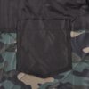 Zdjęcie przedstawia fragment kurtki w kolorze khaki z wzorem moro, z widoczną czarną kieszenią naszytą na materiale. Tkanina ma pikowany wzór, a kieszeń jest prostokątna z zaokrąglonym dołem.