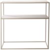 Na zdjęciu znajduje się konsola o prostokątnym kształcie, wykonana z jasnego materiału, z dwoma poziomymi półkami i metalową ramą. Produkt ma minimalistyczny design i piaskowy kolor.