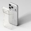 Przezroczysto-brokatowe etui na telefon leży obok smartfona, który ma trzy duże obiektywy aparatu i srebrną obudowę. Etui jest lekko wygięte, a jego powierzchnia pokryta jest drobnymi, błyszczącymi cząstkami.