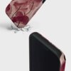 Etui na telefon z motywem różowych kwiatów leży na powierzchni z pęknięciami, a na etui widoczny jest napis "BURGA". Na drugim planie widać zbliżenie na krawędź etui z czarnym wnętrzem.