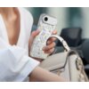 Osoba trzyma telefon w etui z wielokolorowym wzorem kwiatowym. Obok znajduje się jasna torebka z ciemnymi akcentami.