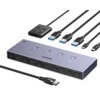 Na zdjęciu znajduje się przełącznik KVM marki UGREEN z kilkoma portami HDMI i USB, a także zestaw kabli z różnymi złączami. Na urządzeniu widoczne są napisy: "UGREEN", "8K", "60Hz", oraz oznaczenia portów takie jak "PC1 Input", "HDMI Video", "USB-C Data".