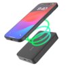 Na zdjęciu widoczny jest czarny powerbank z zielonymi liniami symbolizującymi ładowanie bezprzewodowe oraz smartfon z wyświetlaczem pokazującym godzinę 9:40. Na ekranie smartfona widnieje napis "charging".