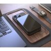 Na zdjęciu znajduje się czarny powerbank z napisem "FIXED" umieszczony na drewnianej podstawce obok smartfona, laptopa i smartwatcha. Powerbank ma gładką powierzchnię i widoczne porty na jednym z boków.