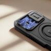 Czarne etui na telefon z widocznym wzorem przypominającym błyskawice wokół otworów na aparat. Na etui znajduje się również okrągły element, prawdopodobnie związany z funkcją MagSafe.