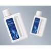 Na zdjęciu widoczne są dwie białe butelki z niebieską etykietą, na której znajduje się napis: "MOVA MULTI-SURFACE FLOOR CLEANER Powerful cleaning for all hard surfaces 16.9 FL OZ 500 mL". Tło jest jednolite, w odcieniach szarości.
