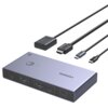 Na zdjęciu znajduje się przełącznik KVM UGREEN CM731 z kilkoma kablami, w tym HDMI i USB-C. Na urządzeniu widoczne są porty oznaczone jako "PC 1" i "PC 2", a także logo "UGREEN" oraz napis "4K@60Hz".