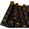Czarna klawiatura z podświetleniem w kolorze pomarańczowym, widoczne klawisze to m.in. "Esc", "Tab", "Caps", "Shift", "Ctrl", "Win", "Alt", oraz klawisze makro "M1" do "M5". W lewym górnym rogu znajduje się pokrętło z ikoną głośnika.