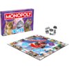 Pudełko gry planszowej "Monopoly Edycja Koty" przedstawia trzy koty w zabawnych okularach i akcesoriach, a na planszy widoczny jest duży obraz kota w czerwonym szaliku. Obok planszy znajdują się metalowe pionki w kształcie różnych przedmiotów.