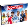 Pudełko gry planszowej z napisem "MONOPOLY" na czerwonym tle oraz "WORLD FOOTBALL STARS" na tle piłki, z ilustracjami sześciu piłkarzy. W lewym dolnym rogu widnieje oznaczenie wiekowe "8+" oraz ikona dwóch graczy.