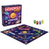 Pudełko i plansza gry "Monopoly Junior Kosmos" przedstawiają kolorowe, uśmiechnięte planety i inne ciała niebieskie na fioletowym tle z napisem "KOSMOS". Obok planszy znajdują się cztery pionki w kolorach zielonym, czerwonym, niebieskim i żółtym.