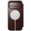 Brązowe etui skórzane z okrągłym białym elementem na środku, przypominającym ładowarkę MagSafe, oraz wąskim poziomym otworem w górnej części. Produkt ma eleganckie wykończenie i jest przeznaczony do telefonu.