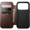 Brązowe skórzane etui z trzema kieszonkami na karty i miejscem na banknoty, obok czarna część z okrągłym wzorem. Na etui widoczny jest napis: "NOMAD Horween Leather Co. Chicago, Est. 1905".