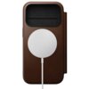 Brązowe etui skórzane z okrągłym, białym elementem na środku oraz czarną kieszonką na górze. Produkt jest przeznaczony do telefonu Apple iPhone 17 Pro.