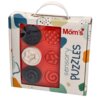 Opakowanie z klockami sensorycznymi, na którym widnieje napis "Mom's sensory PUZZLES", zawiera sześć okrągłych klocków w kolorach czarnym, czerwonym i białym, z różnorodnymi teksturami. Tło opakowania jest kolorowe, z abstrakcyjnymi wzorami.