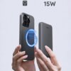 Na zdjęciu widoczny jest szary powerbank z napisem "AUKEY" oraz smartfon z efektem graficznym przedstawiającym magnetyczne połączenie. W górnej części obrazu znajduje się symbol ładowania oraz napis "15W".