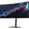 Zakrzywiony monitor z wyświetlanym obrazem przedstawiającym trójwymiarowy napis "GAMING" w futurystycznym stylu, z widocznym logo "GIGABYTE" na dolnej ramce. Tło obrazu jest ciemne, z niebieskimi i czerwonymi akcentami świetlnymi.