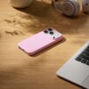 Różowe etui na telefon leży na drewnianym blacie obok otwartego laptopa i słuchawek z widocznym logo "b". Na etui znajduje się napis "beos".