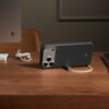 Na zdjęciu widoczne jest granitowo-szare etui na telefon z napisem "beats", umieszczone na drewnianym blacie. Obok etui znajdują się słuchawki oraz fragment monitora.