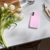 Na zdjęciu widoczne jest różowe etui na telefon z napisem "beets" leżące na białym blacie obok białych tulipanów, drewnianej deski, szklanki z wodą i nożyc ogrodniczych.