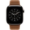 Na zdjęciu widoczny jest smartwatch z okrągłą tarczą, na której znajdują się cyfry i oznaczenia minutowe, z brązowym, karmelem paskiem. Tarcza zegarka ma wskazówki godzinową, minutową i sekundową, a pasek jest wykonany z materiału o fakturze przypominając