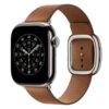 Karmelowy pasek do zegarka Apple Watch z metalową klamrą, przymocowany do zegarka z czarną tarczą analogową z białymi oznaczeniami godzin i minut. Tarcza zegarka wyświetla czas w formacie analogowym z trzema wskazówkami.