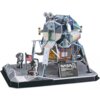 Model 3D przedstawiający moduł księżycowy Apollo 11 z flagą USA i dwoma astronautami na podstawce. Na modelu widoczny jest napis "UNITED STATES", a na tabliczce "NASA APOLLO 11 LUNAR MODULE EAGLE" z dodatkowymi informacjami o lądowaniu.
