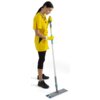 Osoba w żółtym uniformie i żółtych rękawiczkach trzyma mop płaski z szarym uchwytem i niebiesko-białą końcówką czyszczącą. Produkt to "Mop płaski KARCHER TTS Ray 9.212-033.0".