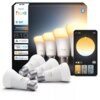 Pudełko z czterema inteligentnymi żarówkami LED marki Philips Hue, model 929003854808, o mocy 6W, z gwintem E27, obsługującymi Bluetooth i ZigBee, z widocznymi ikonami kompatybilności z Alexa, Apple Home i Google Home. Obok pudełka znajduje się wizualizacja aplikacji mobilnej do sterowania oświetleniem, pokazująca opcje zmiany barwy światła.