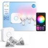 Na zdjęciu znajduje się opakowanie zestawu "PHILIPS hue Essential GU10 Starter kit" z trzema żarówkami LED oraz mostkiem, obok widoczny jest interfejs aplikacji na smartfonie z kołem kolorów. Na opakowaniu widnieje napis "50 W = 4.7 W, 345 lumen", a w rog