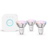 Na zdjęciu widoczne są trzy inteligentne żarówki LED PHILIPS HUE GU10 oraz biały mostek z logo "PHILIPS" i trzema niebieskimi diodami. Żarówki mają srebrne wykończenie i oznaczenie "hue Essential".