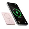 Różowy powerbank z oznaczeniem Qi leży obok smartfona, na którego ekranie widoczny jest symbol ładowania z napisem "75% Charged".