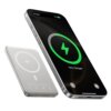 Na zdjęciu widoczny jest smartfon z ekranem pokazującym ikonę ładowania i napis "75% Charged", obok znajduje się powerbank z oznaczeniem "qi" i symbolami certyfikacji. Powerbank ma smukły, prostokątny kształt i metaliczne wykończenie.