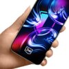Na zdjęciu widoczny jest telefon trzymany w dłoni, z kolorowym, abstrakcyjnym wzorem na ekranie. W dolnej części ekranu znajduje się logo "3mk".