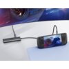 Na zdjęciu widoczny jest hub UGREEN z dwoma portami USB, podłączony do przenośnej konsoli do gier, która wyświetla obraz samochodu wyścigowego. Na hubie znajduje się logo "UGREEN", a w tle widać fragment ekranu z grafiką wyścigową.