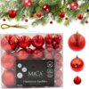 Przezroczyste opakowanie zawiera 46 czerwonych bombek o różnych fakturach i rozmiarach, z widocznym napisem "MICA Decorations" oraz informacją "Christmas baubles recycled plastic". Na górze zdjęcia widoczna jest gałązka choinki ozdobiona czerwonymi bombka