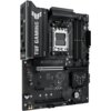 Czarna płyta główna z widocznymi napisami "TUF GAMING" oraz "TUF GAMING B650E-E WIFI", z logo producenta ASUS i oznaczeniami portów oraz złączy. Na płycie znajdują się różne komponenty elektroniczne, w tym gniazdo procesora, sloty RAM i złącza PCIe.
