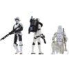 Na zdjęciu znajdują się trzy figurki szturmowców z serii Star Wars, każda w innej pozie i z różnym wyposażeniem. Figurka po lewej trzyma broń, środkowa ma plecak, a prawa siedzi z laską.