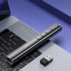 Na zdjęciu znajduje się czarny wskaźnik laserowy z czterema przyciskami, leżący na klawiaturze laptopa obok małego adaptera USB. Na wskaźniku widoczny jest napis "zenwire".