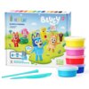 Opakowanie zestawu "HEY CLAY Bluey & Friends" zawiera ilustracje postaci z plasteliny na tle krajobrazu z domem i drzewami oraz napis "BLUEY" z oznaczeniem wieku 3+. Obok opakowania znajdują się stosy kolorowych pojemników z masą plastyczną oraz dwa niebieskie narzędzia do modelowania.